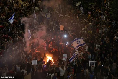 Demonstrators stand around a fire as they protest against the government in Tel Aviv tonight