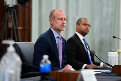 Brendan Carr seated at a hearing, wearing a suit and tie with a microphone in front of him.