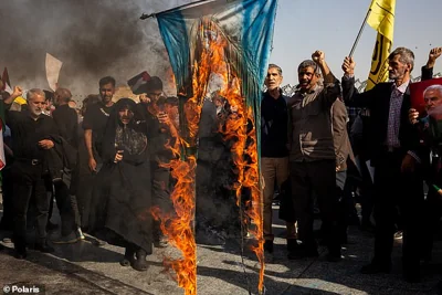 Demonstrators wave flags and carry portraits of slain leaders during a rally in Tehran on October 2