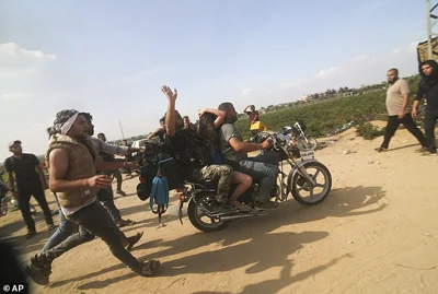 Palestinians transport a captured Israeli civilian, center, from Kfar Azza kibbutz into the Gaza Strip on Saturday, Oct. 7, 2023