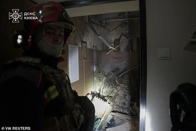 A firefighter stands next to part of a missile that landed inside an apartment block in Kyiv