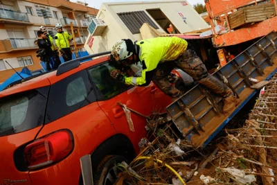 A firefighter looks inside a car after heavy rains in Alfafar, in Valencia