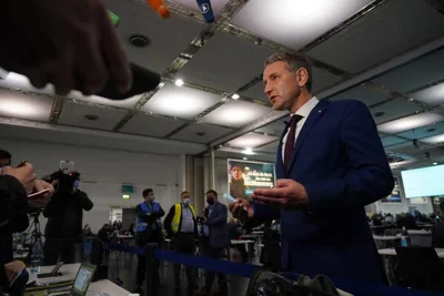 Björn Höcke wears a suit while taking questions from reporters.