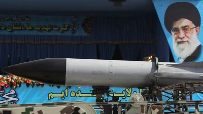 Military truck carries missile past portrait of Iran's Supreme Leader Ayatollah Ali Khamenei