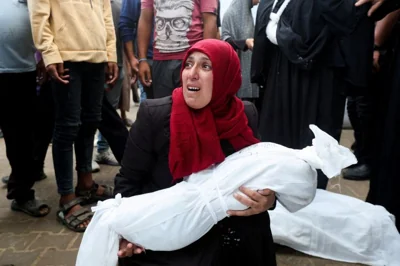 A woman holds the body of a Palestinian child, who was killed in Israeli strikes, amid the Israel-Hamas conflict, at Al-Aqsa Martyrs Hospital in Deir Al-Balah in the central Gaza Strip, October 8, 2024. REUTERS/Ramadan Abed TPX IMAGES OF THE DAY