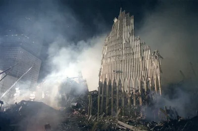 Part of the World Trade Center stands amid rubble and clouds of smoke.