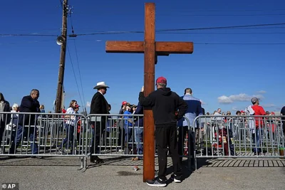 Dan Beasley of Northville, Mich., holds a cross before Republican presidential nominee former President Donald Trump speaks at a campaign rally at the Butler Farm Show