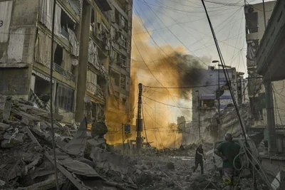 A man runs for cover as a smoke raises in the background following an Israeli airstrike in Beirut, October 4, 2024