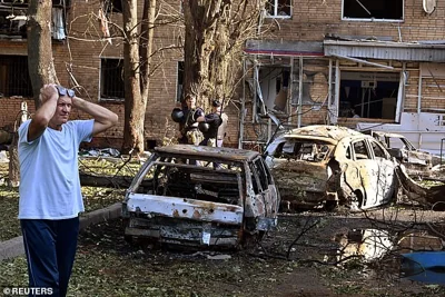 A man reacts while standing next to burnt-out remains of cars in the courtyard of a multi-storey residential building, which according to local authorities was hit by debris from a destroyed Ukrainian missile, in the course of Russia-Ukraine conflict in Kursk, Russia August 11, 2024