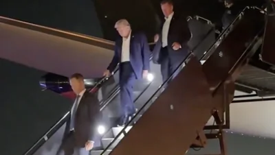 Donald Trump walks down the steps of his plane after the assassination attempt at a rally in Pennsylvania