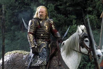 A bearded man in armor sits atop a white horse and appears to be speaking to somebody out of the picture,