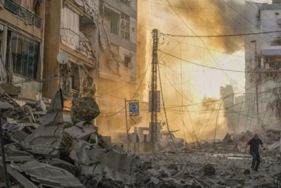 A man runs for cover as a smoke raises in the background following an Israeli airstrike in Dahiyeh, Beirut, Lebanon, Friday, Oct. 4, 2024. (AP Photo/Hassan Ammar)