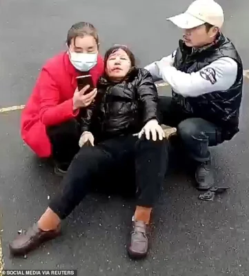 A bloodied and badly bruised woman is seen being helped after she was ran down outside a school