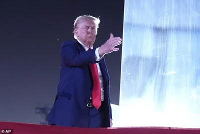 Former President Donald Trump is seen here tapping the bullet-resistant glass after speaking at a campaign event at the Butler Farm Show. He speaks from behind protective screens after surviving an assassination attempt in July