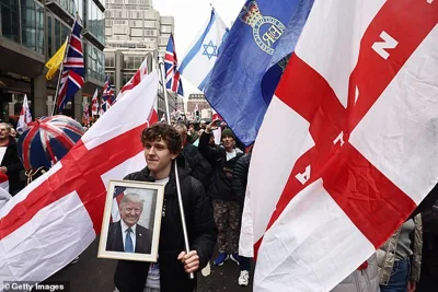 A young man holds a picture of Donald Trump as he marches through London as part of the crowd