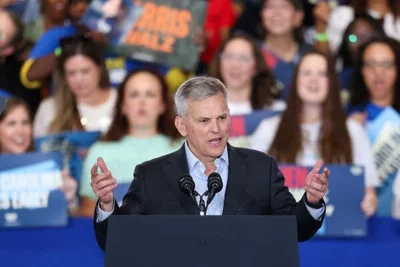 Josh Stein speaks into a microphone, with several supporters behind him.