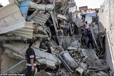 People gather outside a collapsed building as they attempt to extricate a man from underneath the rubble following Israeli bombardment in the Saftawi district in Jabalia in the northern Gaza Strip on October 15, 2024