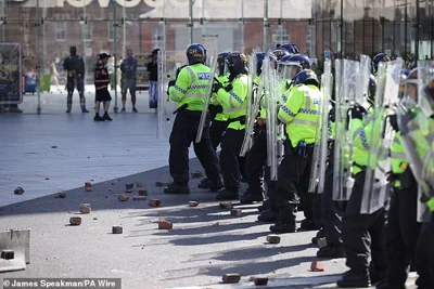 Rubble lies at the feet of police officers thrown by protesters in Liverpool, amid horrifying violence