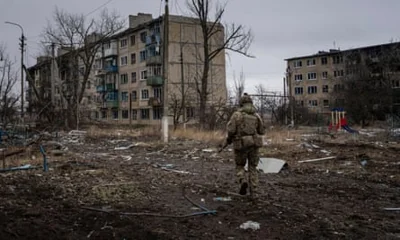 A Ukrainian serviceman runs across empty wasteland between residential blocks