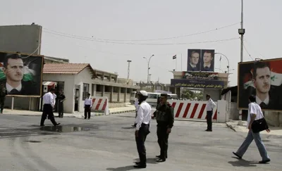 A prison compound with guards standing in the street around an open gate.