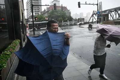 People struggling with their umbrellas on a street in Shanghai. It is raining heavily.