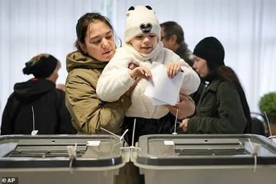 A  mother holds a child as she casts her vote in Chisinau, Moldova, during a presidential election and a referendum