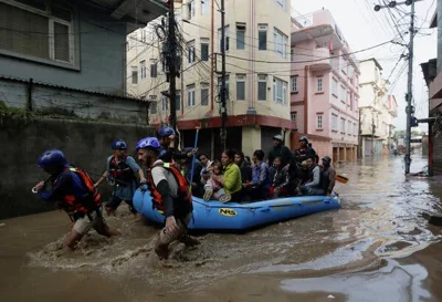 Three men pull a raft filled with people through a flooded urban street.