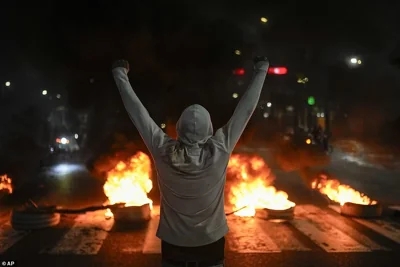 A protestor raises his arms in front of tires on fire in Caracas, Venezuela, Monday, July 29, 2024, the day after the presidential election