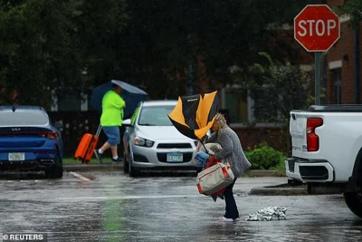 A woman holds an umbrella while arriving at a shelter as Hurricane Milton approaches, in Lakeland, Florida