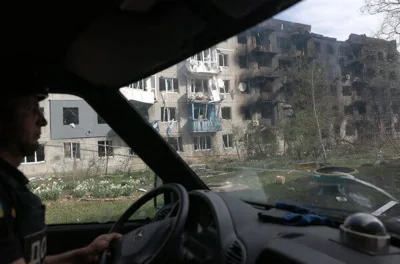 A bombed-out building could be seen through the windows of a vehicle. 