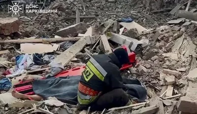 Украинский спасатель сидит рядом с телом жены на развалинах собственного дома, разрушенного российским авиаударом. Великий Бурлук, Украина, 31 июля 2024 года. Скриншот видео ГСЧС Украины