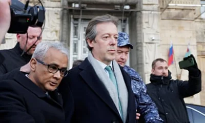 Nigel Casey leaves the foreign ministry in Moscow: he is in front of a large stone building and is being escorted past people taking photographs and video footage