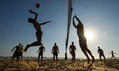 Silhouettes of men playing volleyball before a setting sun