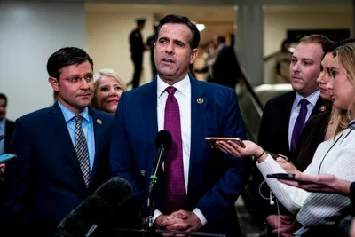 John Ratcliffe speaking into a microphone, surrounded by people.