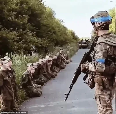 Ukrainian soldier stands guard as he surveys a line of Russian POWs taken in Kursk