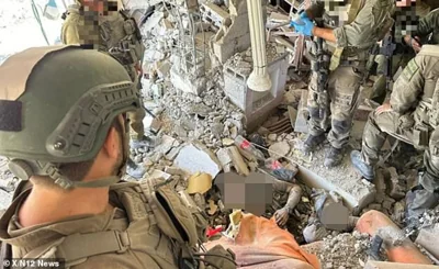 Israeli soldiers are pictured surrounding a corpse which resembles Hamas leader Yahya Sinwar, shown lying in a pile of rubble and with a fatal head wound and body injuries