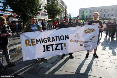 Far-right protesters hold a banner reading 'remigration now' as they march through the streets of Solingen, following a stabbing rampage, on August 26