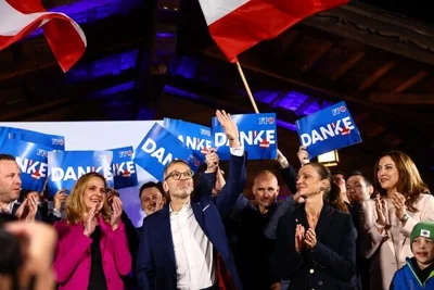 A group of people, some waving blue signs that say, “Danke.” 