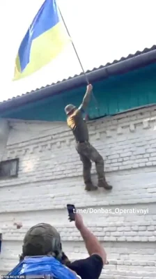 A Ukrainian soldier raises a Ukrainian flag in Guevo, Kursk Oblast, Russia, in an image released on August 11