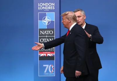 Then NATO Secretary General Jens Stoltenberg, right, directs U.S. President Donald Trump which way to step off the podium