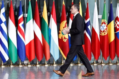 Mr. Kuleba walking past a row of international flags.