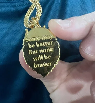 The back of the lion necklace with the engraving: 'Some may be better, but none will be braver'