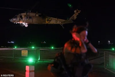 An Israeli soldier stands by as a military helicopter takes off after it dropped off patients that were injured in a drone attack