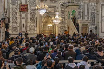 Syrians listen to the sermon by new Syrian prime minister Mohammed al-Bashir