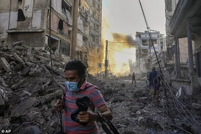 A photographer runs for cover as a smoke raises in the background following an Israeli airstrike in Dahiyeh, Beirut, Lebanon, Friday, Oct. 4, 2024