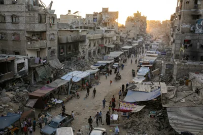 Palestinians displaced by the Israeli bombardment of the Gaza Strip walk through a street market in Khan Younis