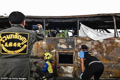 Forensic police officers take photographs as they inspect a burnt-out bus that was carrying students and teachers on the outskirts of Bangkok, on October 1, 2024