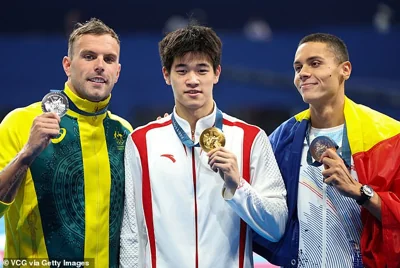 Zhanle stormed to victory in the pool last night, demolishing Aussie Kyle Chalmers (left), whom he finished a whole second ahead of. Zhanle is seen posing with his medal alongside fellow medallists Chalmers and Romanian David Popovici