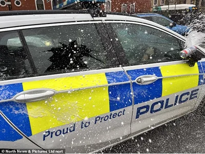 Protesters in Sunderland cover a police car with beer from cans