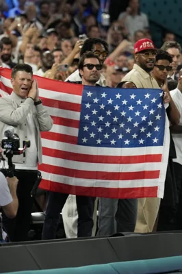 Jimmy Fallon holds up a flag after USA beat France to win gold during a men's gold medal basketball game at Bercy Arena at the 2024 Summer Olympics, Saturday, Aug. 10, 2024, in Paris, France. AP PHOTO